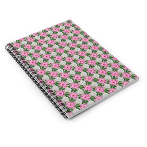 May include: A spiral bound notebook with a pink and white floral pattern. The cover features a repeating pattern of pink and white peonies.