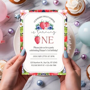 May include: A birthday party invitation with a berry theme. The invitation features watercolor illustrations of strawberries and blueberries, with the text "Our Berry Sweet Harper is turning ONE." The date and time of the party are also included.