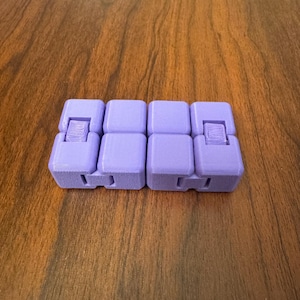 May include: A purple fidget toy made of multiple connected cubes. The toy has a textured surface and is designed to be manipulated with the fingers.