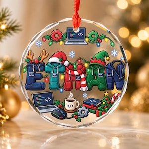 May include: A circular clear acrylic ornament featuring the name ETHAN spelled out in colorful hoodie-shaped letters. The design includes a laptop, a coffee mug with code symbols, a Christmas tree, and festive string lights with a red ribbon hanger.