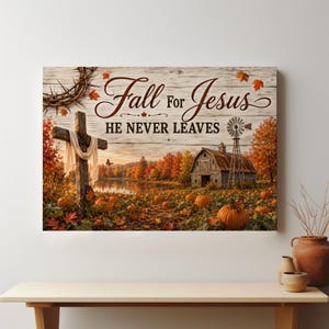 May include: A rectangular wall art print on a white wood-plank background featuring a wooden cross draped in white cloth, a rustic barn, a windmill, and a pumpkin patch. The text reads Fall for Jesus HE NEVER LEAVES in brown script and print.