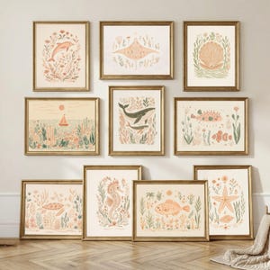 May include: A gallery wall set of ten framed art prints featuring muted peach, sage green, and cream illustrations of marine life including a dolphin, stingray, seashell, whale, pufferfish, sea turtle, seahorse, fish, and starfish among seaweed.