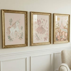 Puede incluir: Conjunto de tres l&aacute;minas art&iacute;sticas enmarcadas con marcos dorados. Las l&aacute;minas presentan ilustraciones caprichosas de un unicornio, un hada y un castillo, todo en tonos rosas y pastel. La obra de arte est&aacute; dise&ntilde;ada para una habitaci&oacute;n infantil.