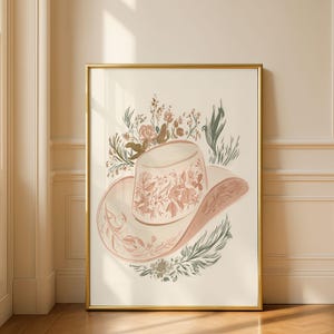 May include: A framed wall art print featuring a light-colored cowboy hat decorated with intricate floral line art in shades of muted pink, terracotta, and sage green, surrounded by botanical illustrations of wildflowers and leafy sprigs.