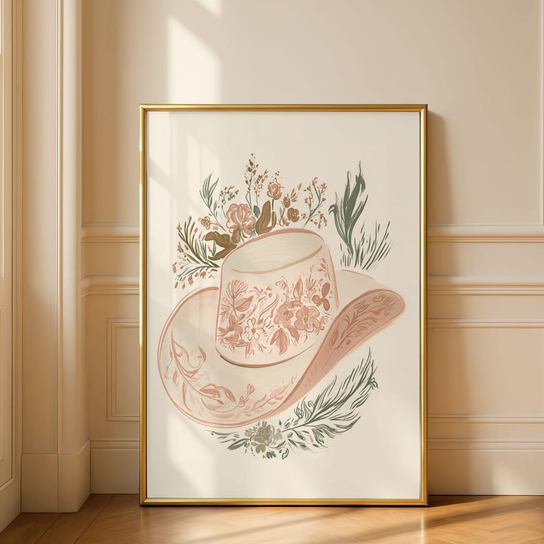 May include: A framed wall art print featuring a light-colored cowboy hat decorated with intricate floral line art in shades of muted pink, terracotta, and sage green, surrounded by botanical illustrations of wildflowers and leafy sprigs.