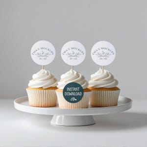 Könnte beinhalten: Drei Cupcakes mit weißem Zuckerguss und runden Toppern auf einer weißen Tortenplatte. Die Topper tragen den Text "EMA'S MOCKUPS" und "JPG-PSD". Ein Cupcake hat einen tealfarbenen Aufkleber mit "INSTANT DOWNLOAD".