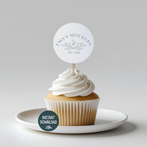 Könnte beinhalten: Ein Cupcake mit weißem Zuckerguss, einer weißen Papierform und einem runden Topper mit der Aufschrift "Ema's Mockups" und einem floralen Design. Der Cupcake steht auf einem weißen Teller, mit einem teal-farbenen "Instant Download" Aufkleber.