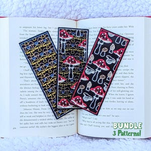 May include: Three rectangular fabric bookmarks featuring embroidered mushroom patterns in red, yellow, and white thread on a black background. The bookmarks are displayed on an open book with the text BUNDLE 3 Patterns! visible in the corner.