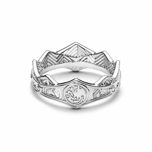Könnte beinhalten: Ein silberfarbener Ring mit einem kronenartigen Design und einem gezackten, spitzen oberen Rand. Das Band ist mit einem sich wiederholenden geometrischen Muster und einem zentralen kreisförmigen Emblem mit einem Drachenmotiv verziert.