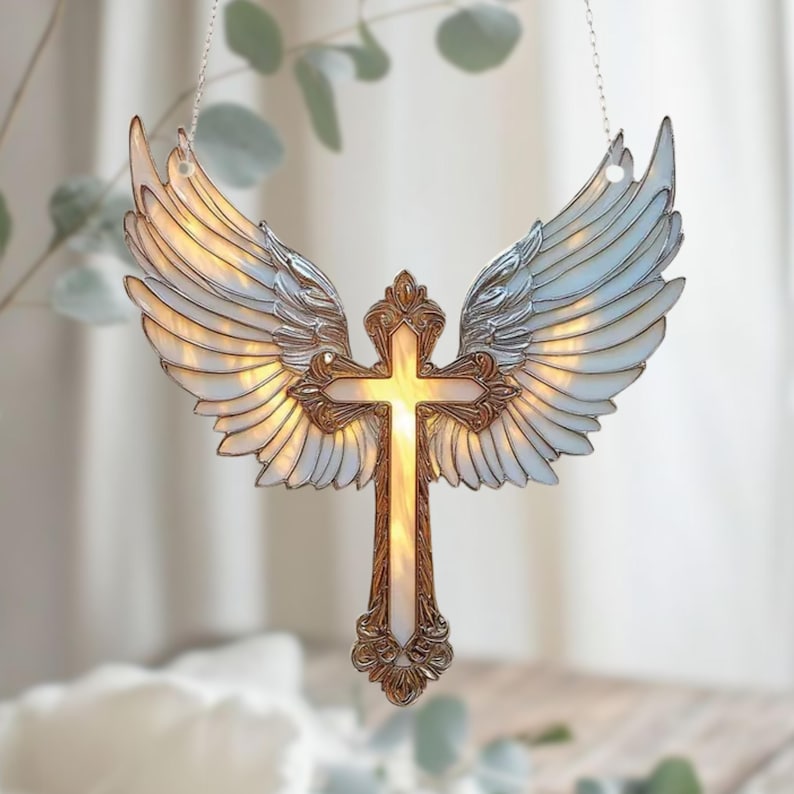 May include: A decorative angel-wing cross pendant. The cross is gold-toned with a white center, and the wings are iridescent. The pendant hangs from a silver chain. The wings are spread wide, and the cross is centered.