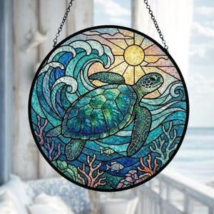 May include: Round stained glass window art featuring a sea turtle swimming in the ocean. The design includes a sun, waves, coral, and fish, with a black border and hanging chain. The colors are shades of blue, green, yellow, and orange.