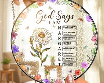 May include: Round glass wall art with a black metal frame, featuring the text "God Says I AM" and a floral design. The artwork includes a daisy and colorful flowers, with the words "Made New", "Accepted", "Redeemed", "Gifted", "Abundant", "Equipped", and "Treasured".