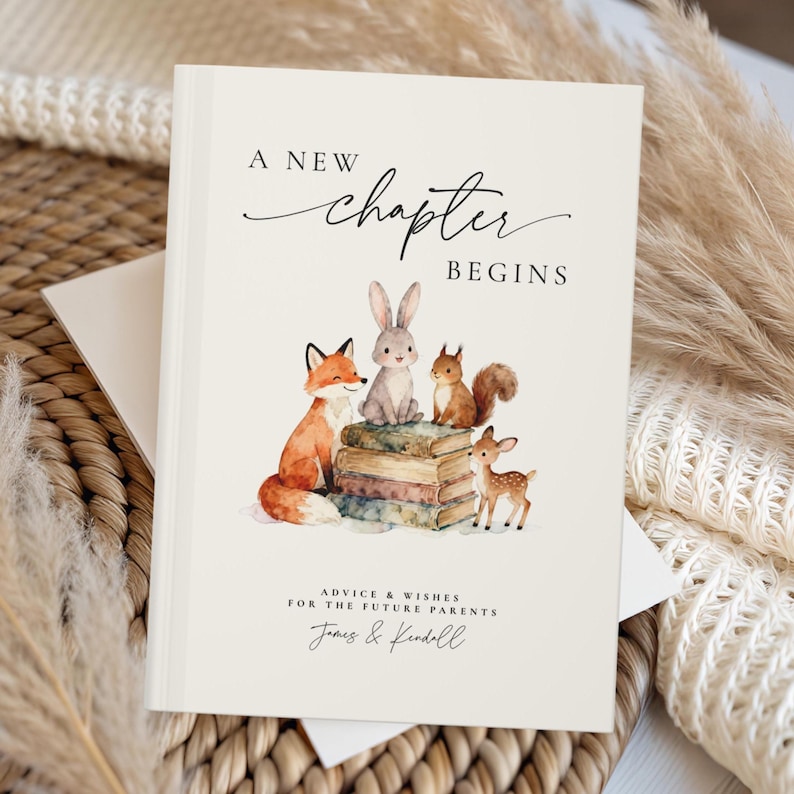 May include: A hardcover book with the words "A New Chapter Begins" in elegant script. The cover features watercolor illustrations of a fox, rabbit, squirrel, and deer atop a stack of books. Text below reads "Advice & Wishes for the Future Parents".