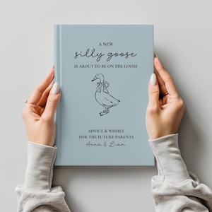 Op de afbeelding: Een lichtblauw boek met de tekst "A New Silly Goose is About to Be on the Loose" en een tekening van een gans. Het boek bevat ook de tekst "Advice & Wishes for the Future Parents Anna & Liam."
