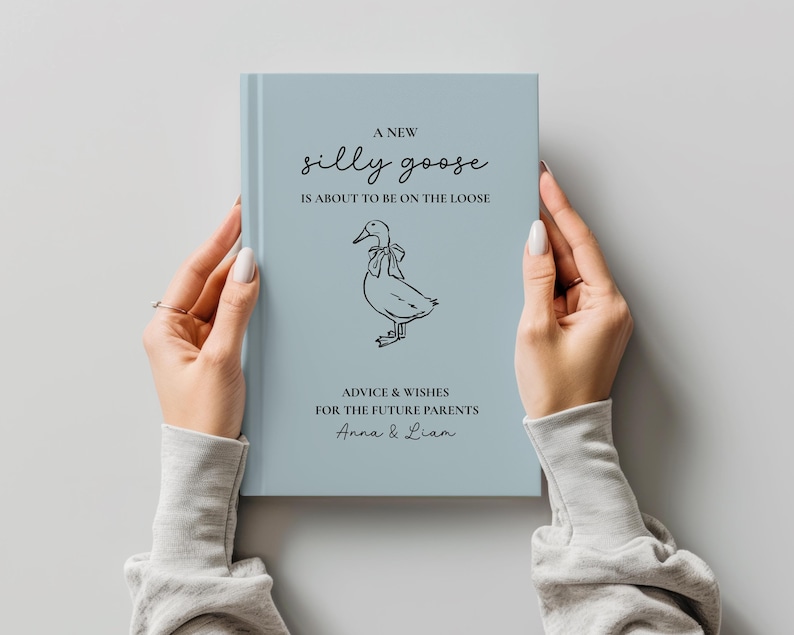Op de afbeelding: Een lichtblauw boek met de tekst "A New Silly Goose is About to Be on the Loose" en een tekening van een gans. Het boek bevat ook de tekst "Advice & Wishes for the Future Parents Anna & Liam."