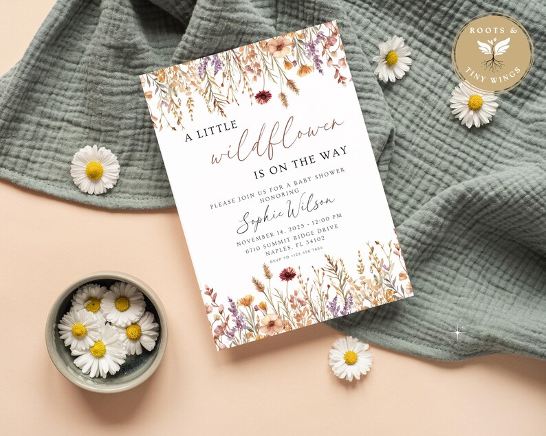 以下が含まれることがあります： ベビーシャワーの招待状。テキストは「A Little Wildflower Is On The Way」とあり、Sophie Wilsonのベビーシャワーの詳細が記載されています。招待状は、紫、黄色、茶色の水彩画の花で囲まれています。