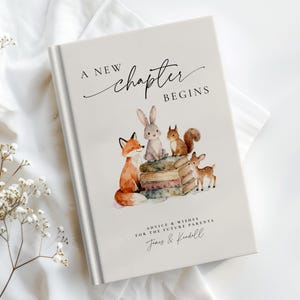 May include: A hardcover baby memory book with the text "A New Chapter Begins." The cover features watercolor illustrations of a fox, rabbit, squirrel, and deer. The book includes the text "Advice & Wishes For The Future Parents" and a personalized name.