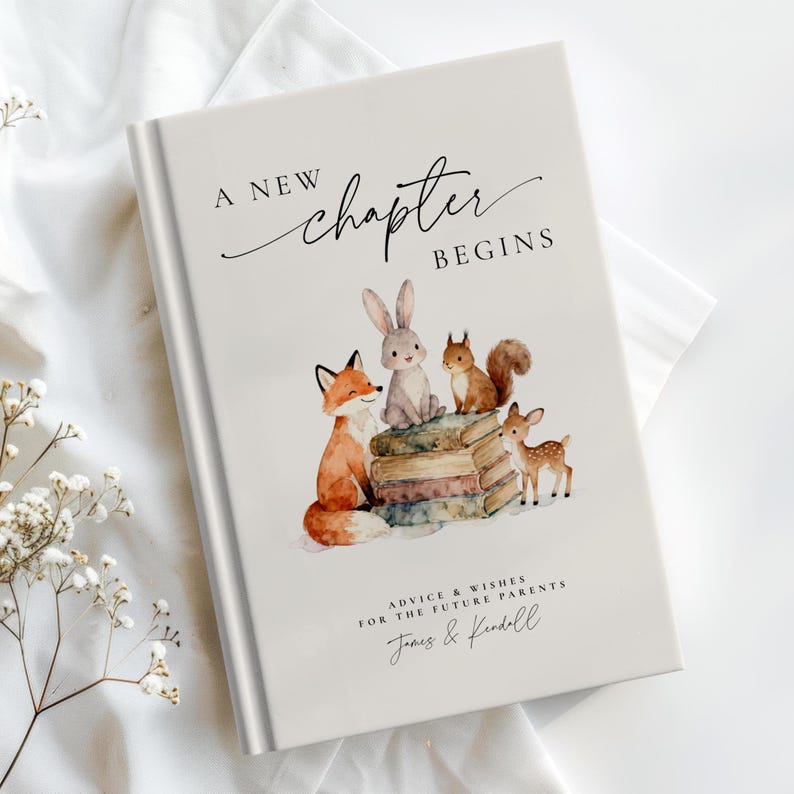 May include: A hardcover baby memory book with the text "A New Chapter Begins." The cover features watercolor illustrations of a fox, rabbit, squirrel, and deer. The book includes the text "Advice & Wishes For The Future Parents" and a personalized name.