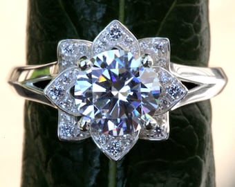 May include: A silver ring with a large, clear, round gemstone surrounded by smaller gemstones in a flower-shaped setting.