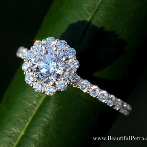 May include: A silver engagement ring with a large round center diamond surrounded by a halo of smaller diamonds. The band is also set with smaller diamonds.