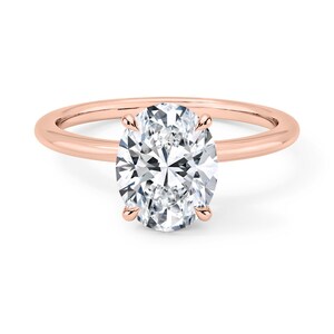 May include: A rose gold engagement ring with a large oval-shaped diamond.