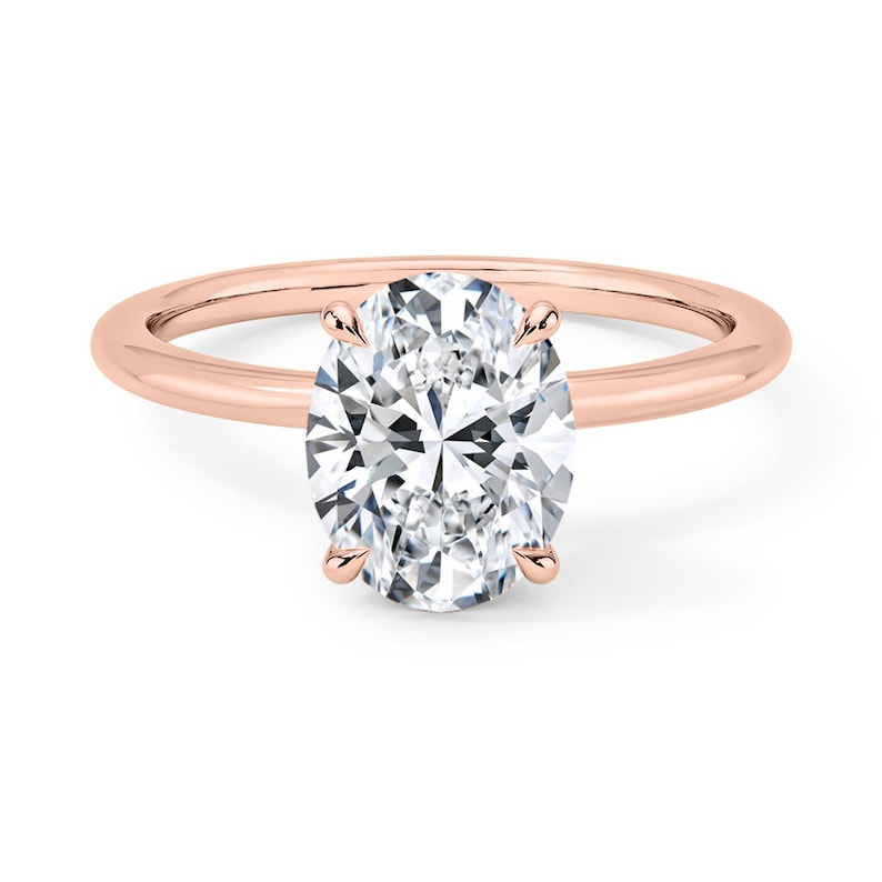 May include: A rose gold engagement ring with a large oval-shaped diamond.
