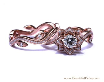 May include: Rose gold engagement ring set with a floral design. The center stone is a round brilliant diamond surrounded by smaller diamonds. The band is a delicate, twisting vine with leaves and diamonds.