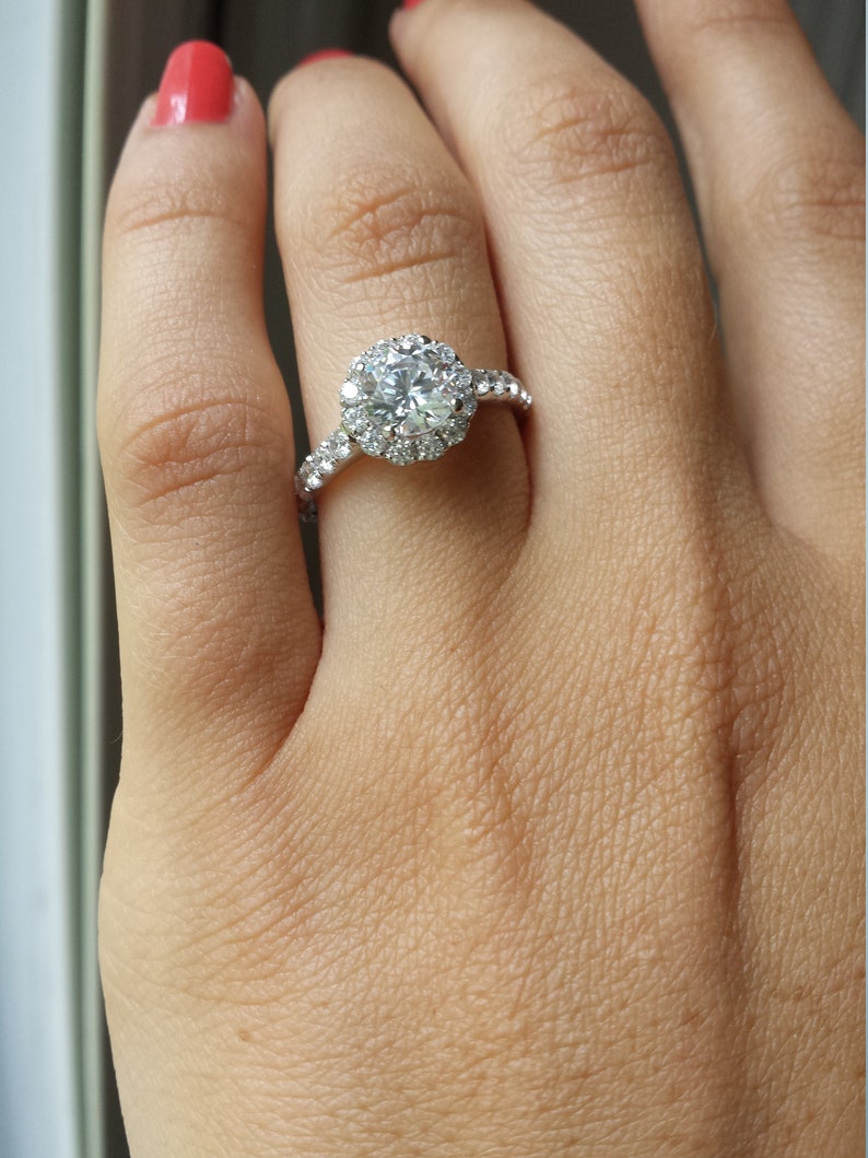 Op de afbeelding: Een zilveren ring met een grote, ronde, heldere diamant omgeven door een halo van kleinere diamanten.