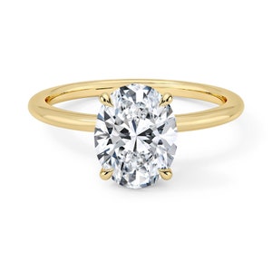 May include: A gold band ring with a large oval-shaped diamond.