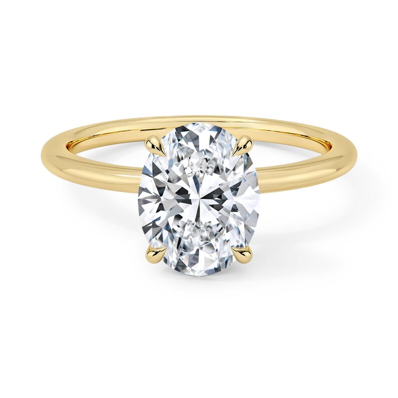 May include: A gold band ring with a large oval-shaped diamond.