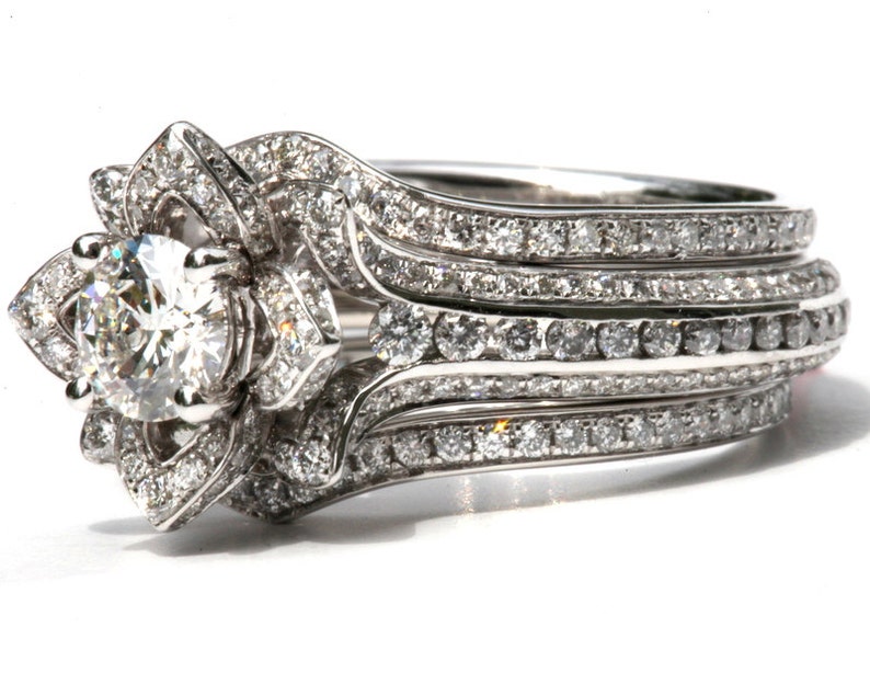 Puede incluir: Un anillo de compromiso de plata con un gran diamante redondo central rodeado de diamantes m&aacute;s peque&ntilde;os. La banda est&aacute; adornada con varias filas de diamantes m&aacute;s peque&ntilde;os.
