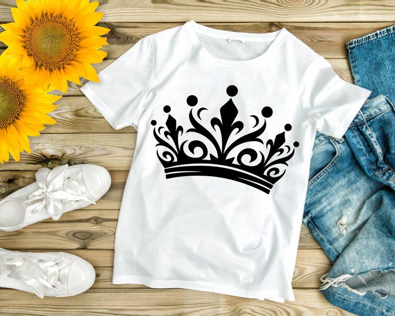 May include: White t-shirt with a black crown graphic design. The crown has a detailed ornate design with a pointed top and a thick band.
