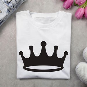 May include: White t-shirt with a black crown graphic.