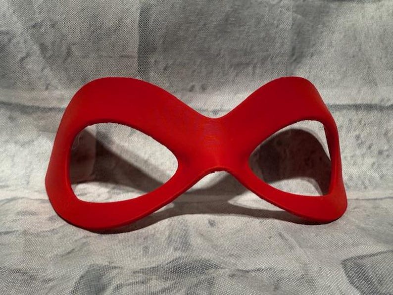 Puede incluir: Una m&aacute;scara de ojos roja brillante con un dise&ntilde;o curvo. La m&aacute;scara presenta dos grandes aberturas para los ojos y un acabado liso y mate. La m&aacute;scara est&aacute; dise&ntilde;ada para adaptarse sobre los ojos y la nariz, y probablemente se utiliza para fines de disfraz o cosplay.