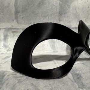 Puede incluir: Una m&aacute;scara de ojos negra con un dise&ntilde;o curvo. La m&aacute;scara tiene un acabado liso y mate y est&aacute; dise&ntilde;ada para cubrir los ojos y el puente de la nariz. La m&aacute;scara probablemente est&aacute; hecha de un material flexible.