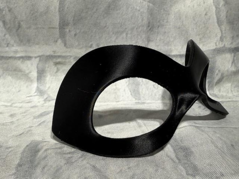 Puede incluir: Una m&aacute;scara de ojos negra con un dise&ntilde;o curvo. La m&aacute;scara tiene un acabado liso y mate y est&aacute; dise&ntilde;ada para cubrir los ojos y el puente de la nariz. La m&aacute;scara probablemente est&aacute; hecha de un material flexible.