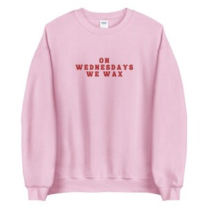 May include: Pink sweatshirt with the text "ON WEDNESDAYS WE WAX" in red.