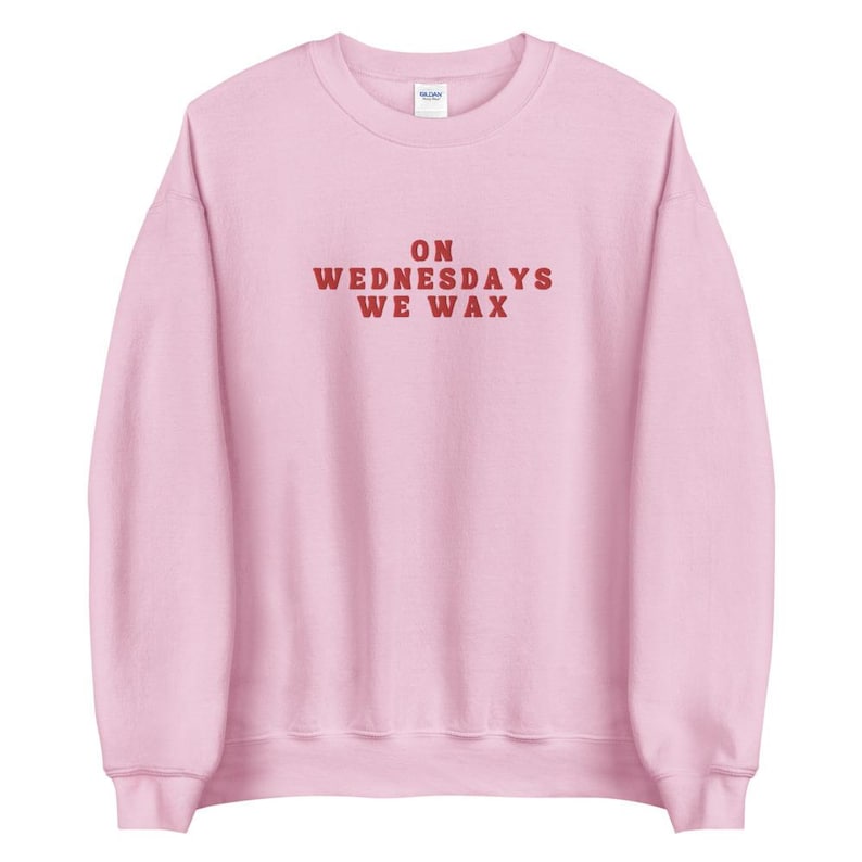 May include: Pink sweatshirt with the text "ON WEDNESDAYS WE WAX" in red.