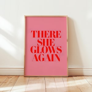 May include: A pink framed print with the text "THERE SHE GLOWS AGAIN" in red.