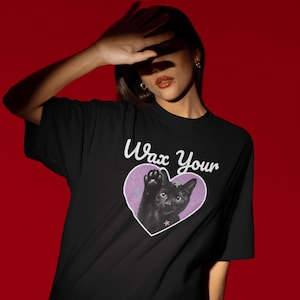 May include: Black t-shirt with a purple heart graphic featuring a black cat with a paw raised. The text "Wax Your" is above the heart.