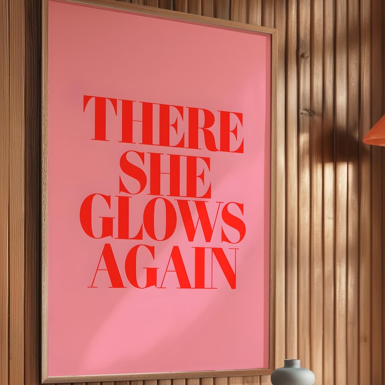 May include: A pink poster with the text "THERE SHE GLOWS AGAIN" in red.