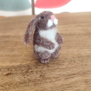Könnte beinhalten: Eine braune und weiße Nadelfilz-Hasenfigur. Der Hase hat einen weißen Bauch und eine rosa Nase.