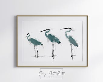 May include: A framed print showing three teal herons in a minimalist style. The birds have long legs and beaks, set against a white background. The artwork is framed in a gold-coloured frame. The text "Gray Art Prints" is at the bottom.
