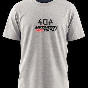 May include: A light gray t-shirt with the text "404 MOTIVATION NOT FOUND" printed in black and red. The shirt has a crew neck and short sleeves. The design is centered on the chest.