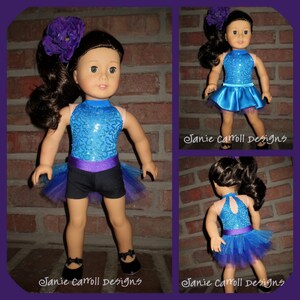 May include: A blue and purple sequined leotard with a black skirt and a tulle overlay. The doll is wearing black shoes and a purple flower in her hair. The image is captioned "Janie Carroll Designs".
