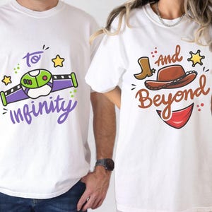 May include: Two white t-shirts with matching graphics. One shirt features a green and purple space ranger design with the words "to infinity". The other shirt has a cowboy hat, boot, and the words "and beyond".