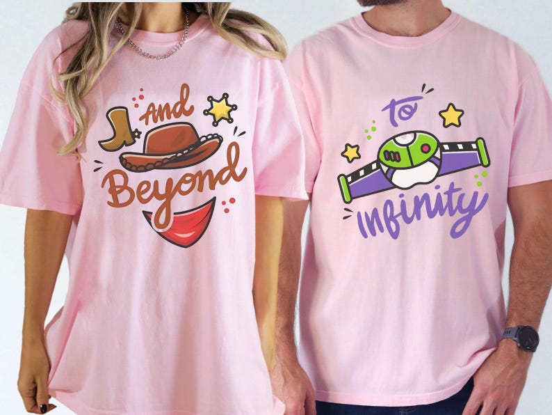May include: Two light pink t-shirts. One shirt has a cartoon cowboy hat and boot with the words "And Beyond". The other shirt has a cartoon spaceship with the words "To Infinity".