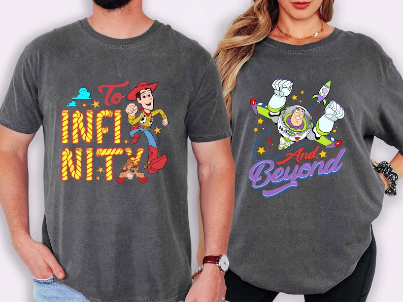 May include: Two charcoal grey t-shirts with Toy Story graphics. One shirt features Woody with the text "To Infinity" in yellow and "Nity" in orange. The other shirt has Buzz Lightyear with the text "And Beyond" in purple.