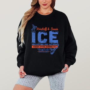 May include: Black sweatshirt featuring the text "Kristoff & Sven's ICE" in blue and orange. The design includes character illustrations and the words "Harvesting and Delivery" and "Winter-Spring-Summer-Fall".