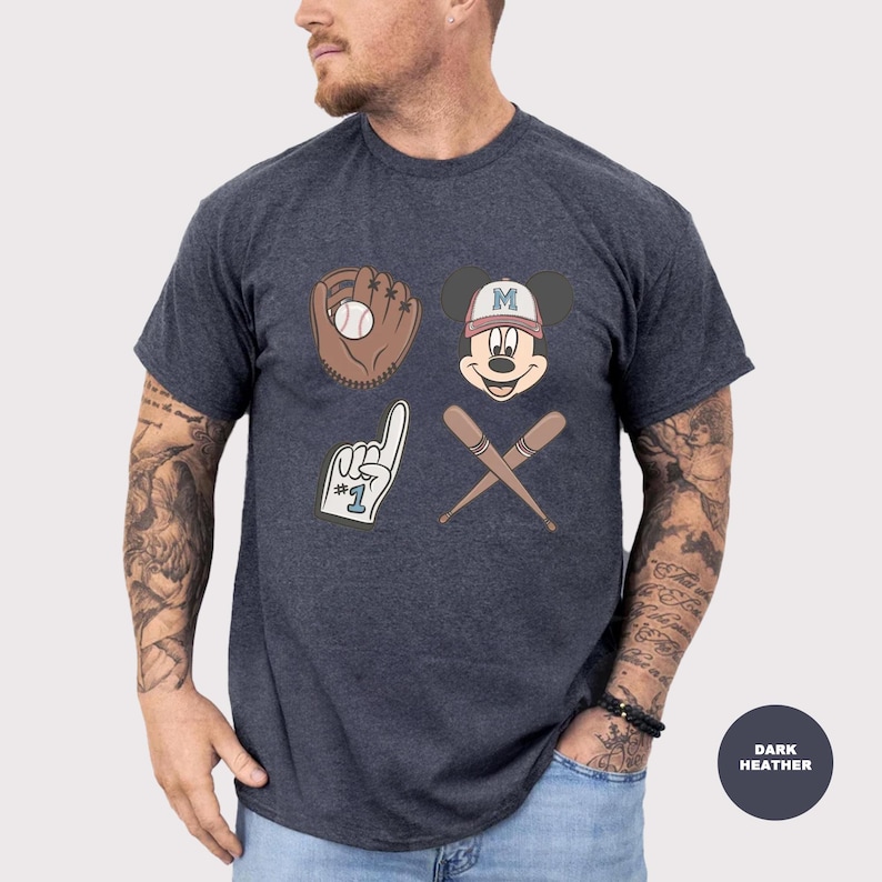 May include: Dark heather gray t-shirt featuring baseball-themed graphics. The design includes a baseball glove with a ball, Mickey Mouse wearing a baseball cap, crossed baseball bats, and a foam finger.